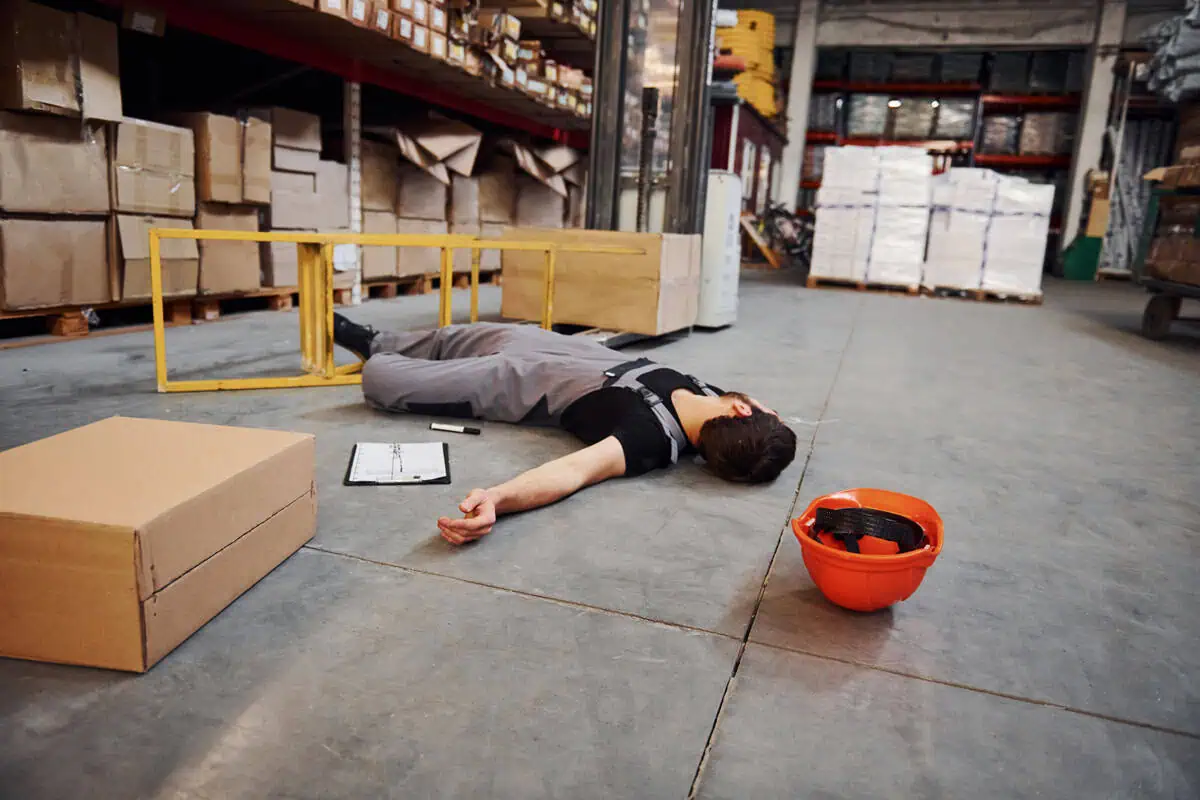 Determining Liability for a Slip-and-Fall Accident warehouse worker on floor after fall near ladder and clipboard