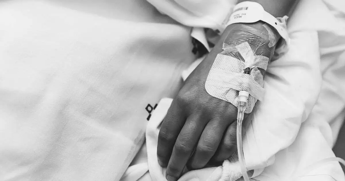 The Costs of Catastrophic Injuries Hand with medical IV in it.