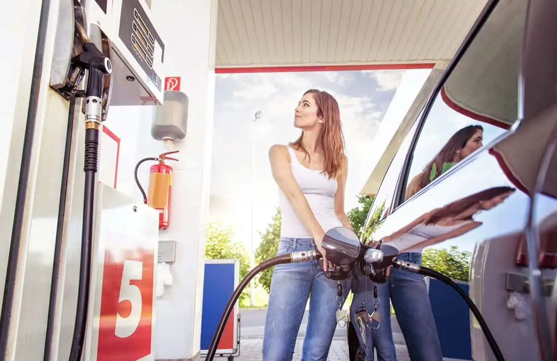 Environmental Costs of Lower Gas Prices woman pumping gas