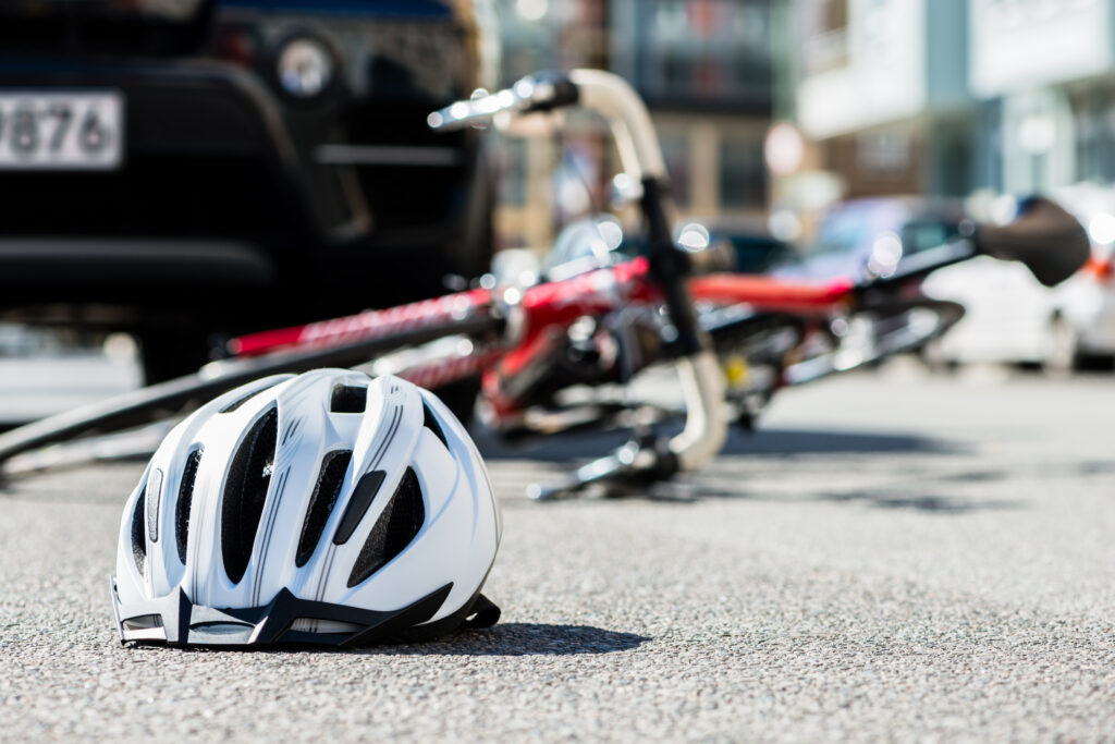 Close-up,Of,A,Bicycling,Helmet,Fallen,On,The,Asphalt,Next