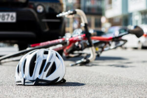 Close-up,Of,A,Bicycling,Helmet,Fallen,On,The,Asphalt,Next