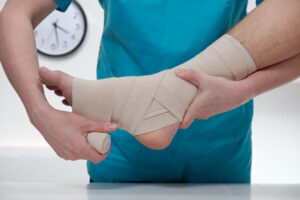 Close-up of doctor bandaging foot of patient at doctor's office.