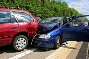 A blue car has rear-ended a red SUV on a road; both vehicles have visible damage, and a car door is open.