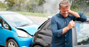 man walking away from car accident. holding neck, clearly in pain