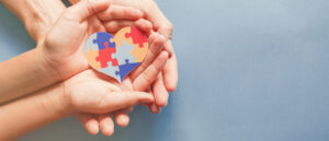 Adult,And,Child,Hands,Holding,Jigsaw,Puzzle,Heart,Shape,,Autism