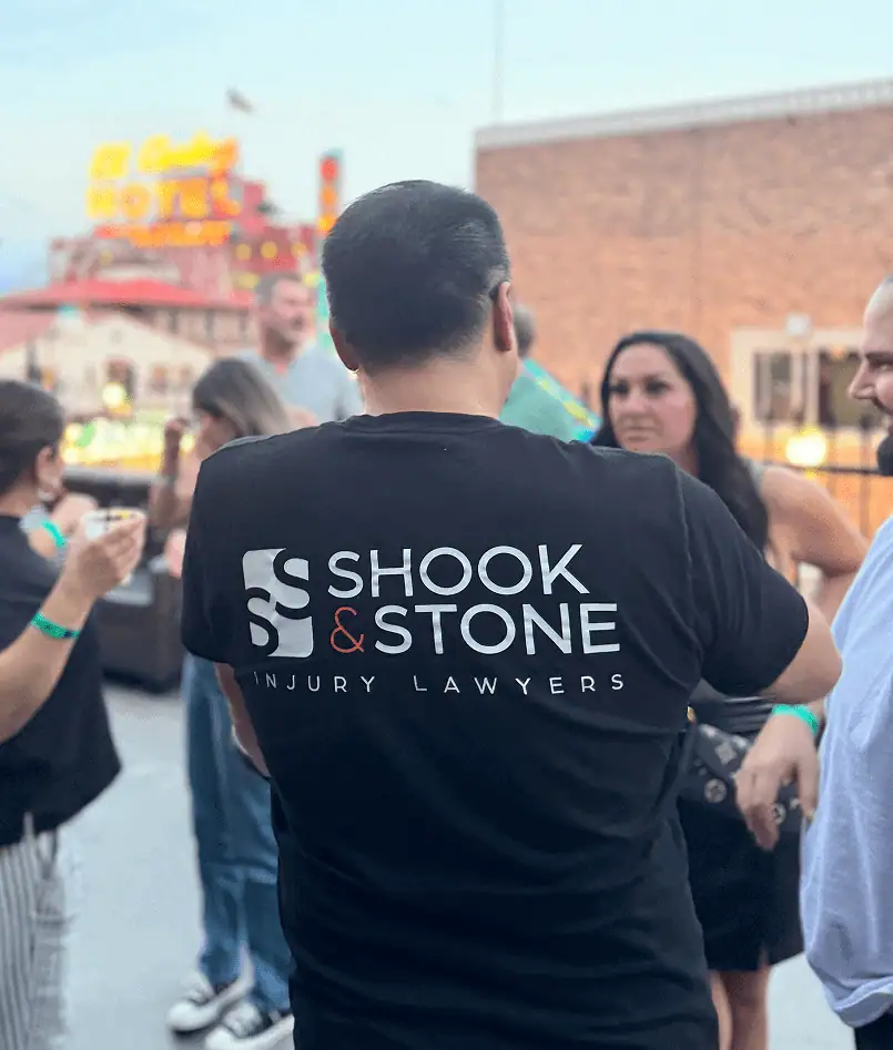 A man stands outdoors wearing a black T-shirt that reads 