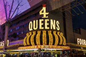Brightly lit "4 Queens" casino sign at night in downtown Las Vegas, featuring a gold crown and surrounding lights.