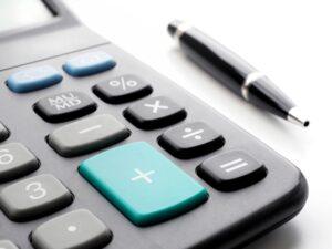 A calculator sitting by a pen. You can use a personal injury settlement calculator to estimate the value of your legal claim.