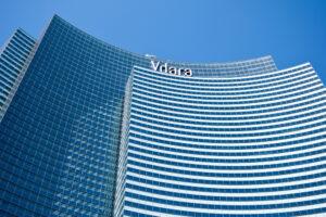 Curved glass facade of the Vdara hotel in Las Vegas, viewed from below against a clear blue sky.