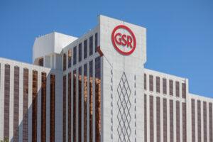 A tall building with brown-tinted windows features a large red "GSR" logo near the top against a clear blue sky.