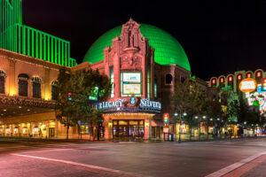 Nighttime view of the Silver Legacy Resort Casino with its distinctive green dome and illuminated signage, located on a quiet street corner in downtown Reno, Nevada.