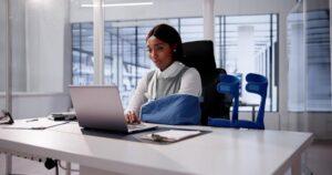 Worker With Crutches At Workplace. Social Security Compensation
