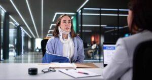 injured woman wearing neck brace and arm sling meeting with insurance representative