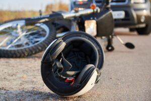 A helmet on the ground next to a crashed motorcycle. Why do I need a specialized lawyer for a motorcycle accident claim?