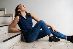 A woman holding her back after slipping and falling on stairs